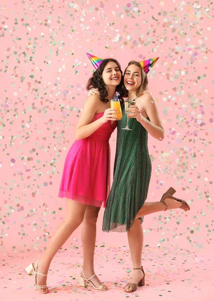 Happy young women with cocktails celebrating Birthday on pink background