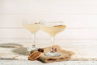 Beyaz ahşap masada bir bardak lezzetli martini ve limon.
