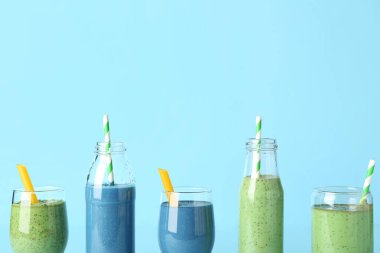 Kadehler ve farklı lezzetli içecekler mavi arka planda pipetlerle