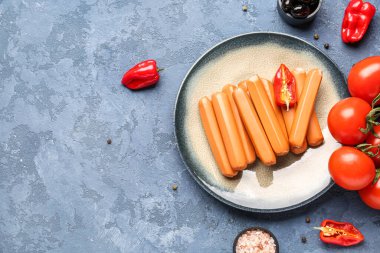 Mavi arka planda sosis, domates ve zeytinli tabak.