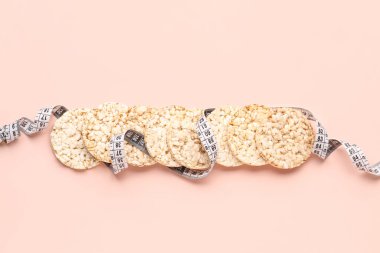 Pembe arka planda pirinç kekleri ve mezura. Diyet kavramı