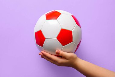 Leylak arka planında futbol topu olan el.
