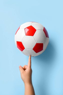 Açık mavi zemin üzerinde futbol topu ile el