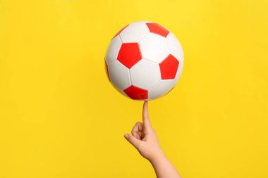 Sarı zemin üzerinde futbol topu olan çocuk eli