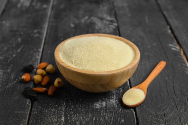 Bir kase çiğ irmik ve koyu ahşap arka planda fındık.