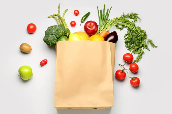 Paper bag with vegetables and fruits on grey background