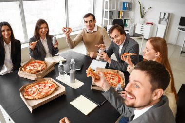 Ofisinde lezzetli pizzaları olan bir grup iş adamı.
