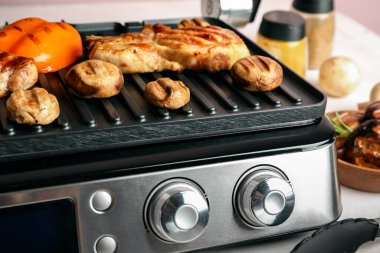 Lezzetli biftek ve sebzeli modern elektrikli ızgara, yakın plan.