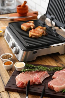 Ahşap tahta, çiğ et ve modern elektrikli ızgara.