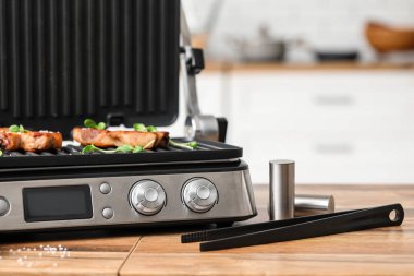 Mutfakta lezzetli biftekleri olan modern elektrikli ızgara, yakın plan.