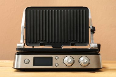 Ahşap masa üzerinde bej arka planda açık kapaklı modern elektrikli ızgara