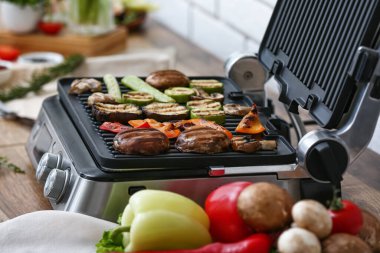 Mutfaktaki masada lezzetli sebzelerle modern elektrikli ızgara.