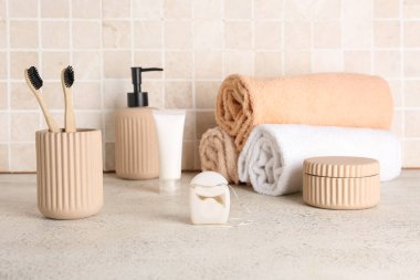 Diş ipi ve banyo aksesuarları fayans duvarının yanındaki masada.