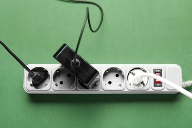 Yeşil arka planda prizleri olan elektrik uzatma kablosu
