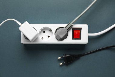 Gri arka planda prizleri olan elektrik uzatma kablosu