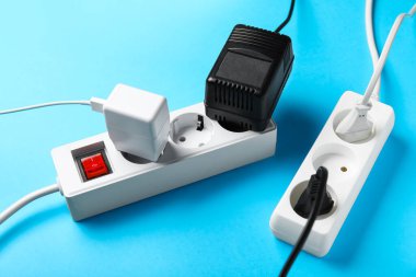 Mavi arkaplanda prizleri olan elektrik uzatma kabloları