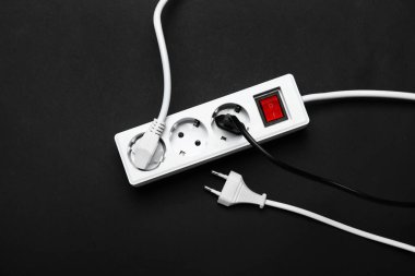 Siyah arkaplanda prizleri olan elektrik uzatma kablosu