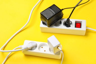 Sarı arka planda prizleri olan elektrik uzatma kabloları