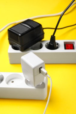 Sarı arka planda prizleri olan elektrik uzatma kabloları