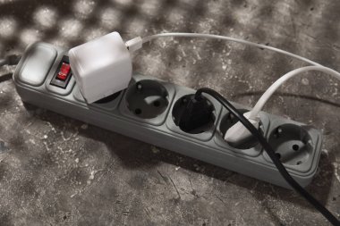 Gri grunge arka planında prizleri olan elektrik uzatma kablosu