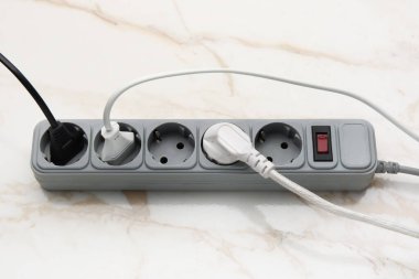 Beyaz mermer arka planda prizleri olan elektrik uzatma kablosu