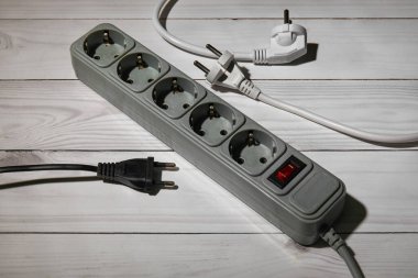 Elektrik uzatma kablosu ve beyaz ahşap zemindeki fişler.