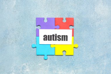 Grunge arkaplanında yapboz parçaları olan kelime AUTISM