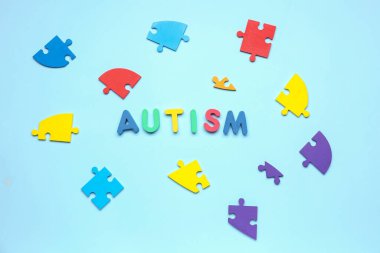 Mavi arkaplanda yapboz parçaları olan kelime AUTISM