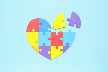 Mavi arka plandaki yapboz parçalarından yapılmış kalp. Dünya Otizm Farkındalık Günü