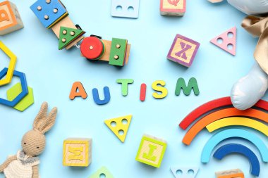 Mavi arka planda bebek oyuncakları olan kelime AUTISM. Dünya Otizm Farkındalık Günü