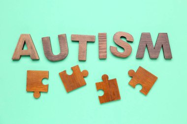 Yeşil arkaplanda yapboz parçaları olan kelime AUTISM