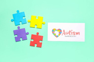 AUTISM AVARENESS GÜNÜ ve yeşil arkaplanda yapboz parçaları içeren kağıt