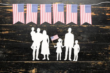 Koyu ahşap arka planda Amerikan bayrakları olan aile figürleri. Anma Günü kutlaması