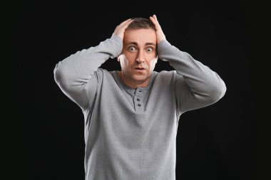 Siyah arka planda korkmuş olgun bir adam.