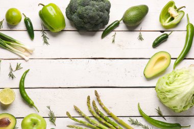 Beyaz ahşap arka planda farklı yeşil sebzelerden yapılmış çerçeve