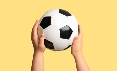 Bej arka planda futbol topu olan çocuk elleri