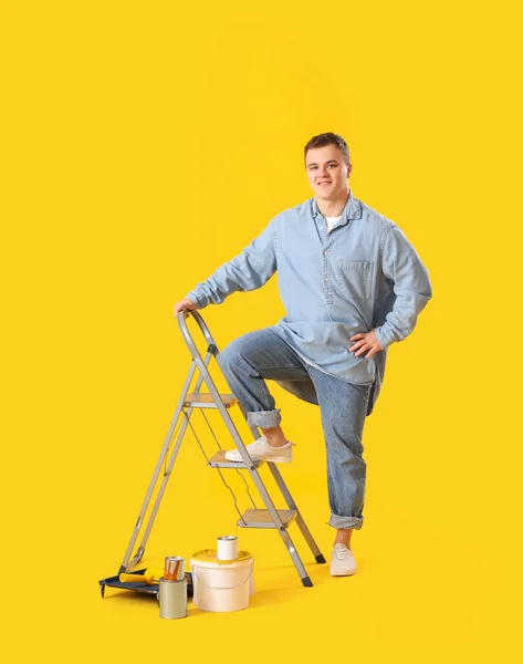 Молодой Человек Лестницей Банками Краски Желтом Фоне — стоковое фото