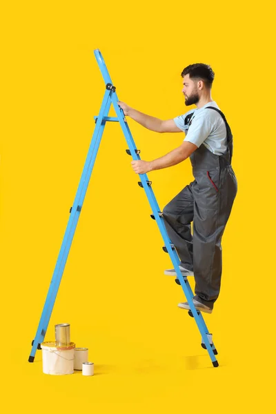 Male Worker Ladder Cans Paint Yellow Background —  Fotos de Stock