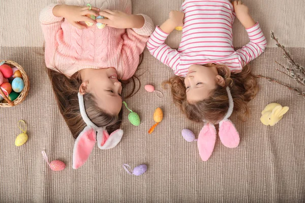 小さな女の子でウサギの耳とともにイースターの卵が家に横たわっています トップビュー — ストック写真