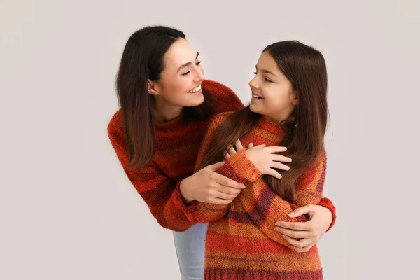 小さな女の子と彼女の母親で暖かいですセーター巨大上の灰色の背景 — ストック写真