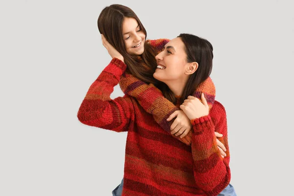 小さな女の子と彼女の母親で暖かいですセーター巨大上の灰色の背景 — ストック写真