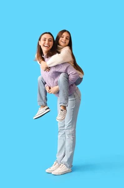 小さな女の子と彼女の母親で暖かいセーターで青の背景 — ストック写真