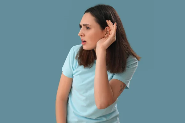 Mujer Joven Tratando Escuchar Algo Sobre Fondo Azul —  Fotos de Stock