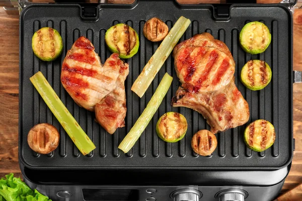 Moderner Elektrogrill Mit Leckeren Steaks Und Gemüse Auf Holzboden — Stockfoto