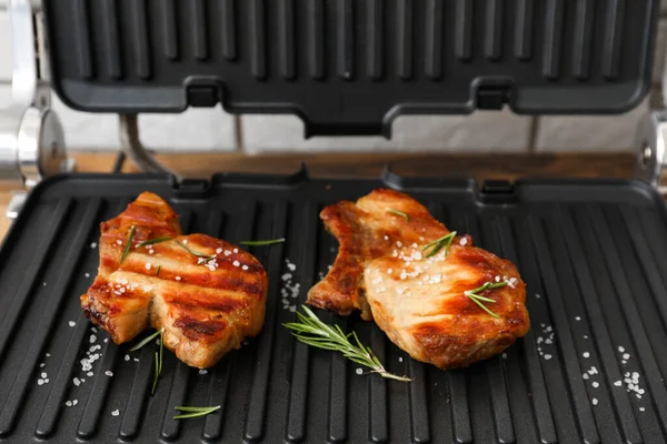 stock image Modern electric grill with tasty steaks on table, closeup