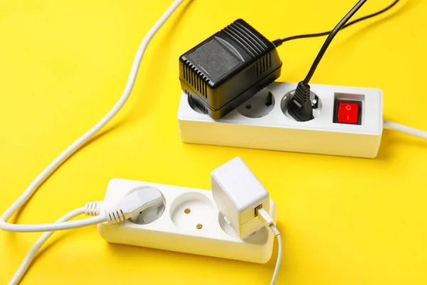 Electric extension cords with plugs on yellow background