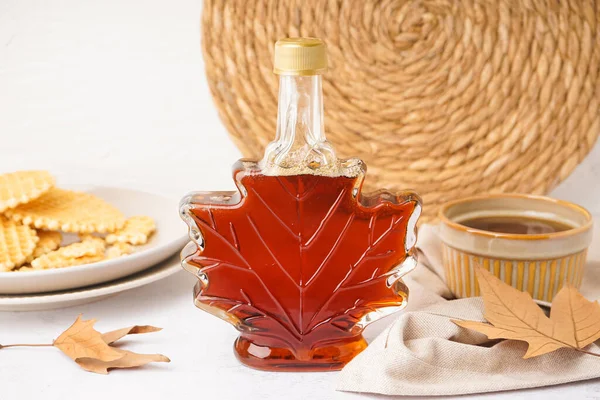 Beautiful composition with bottle of maple syrup and waffles on white background