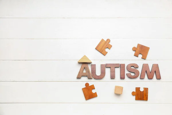Word Autism Puzzle Pieces Baby Toys White Wooden Background — Stock Photo, Image