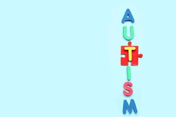 Word AUTISM with puzzle piece on blue background