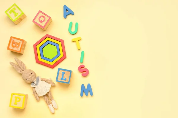 Word AUTISM with baby toys on beige background